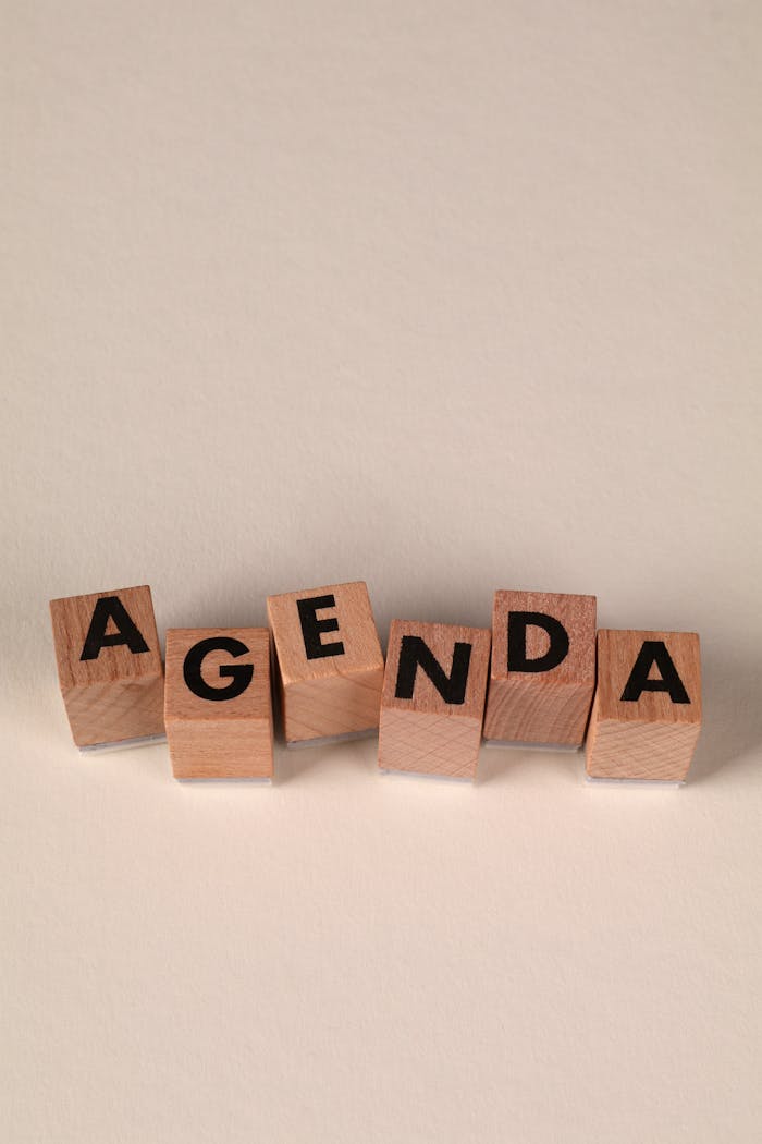 Services Wooden blocks arranged to spell 'Agenda' on a beige background, emphasizing planning and organization.