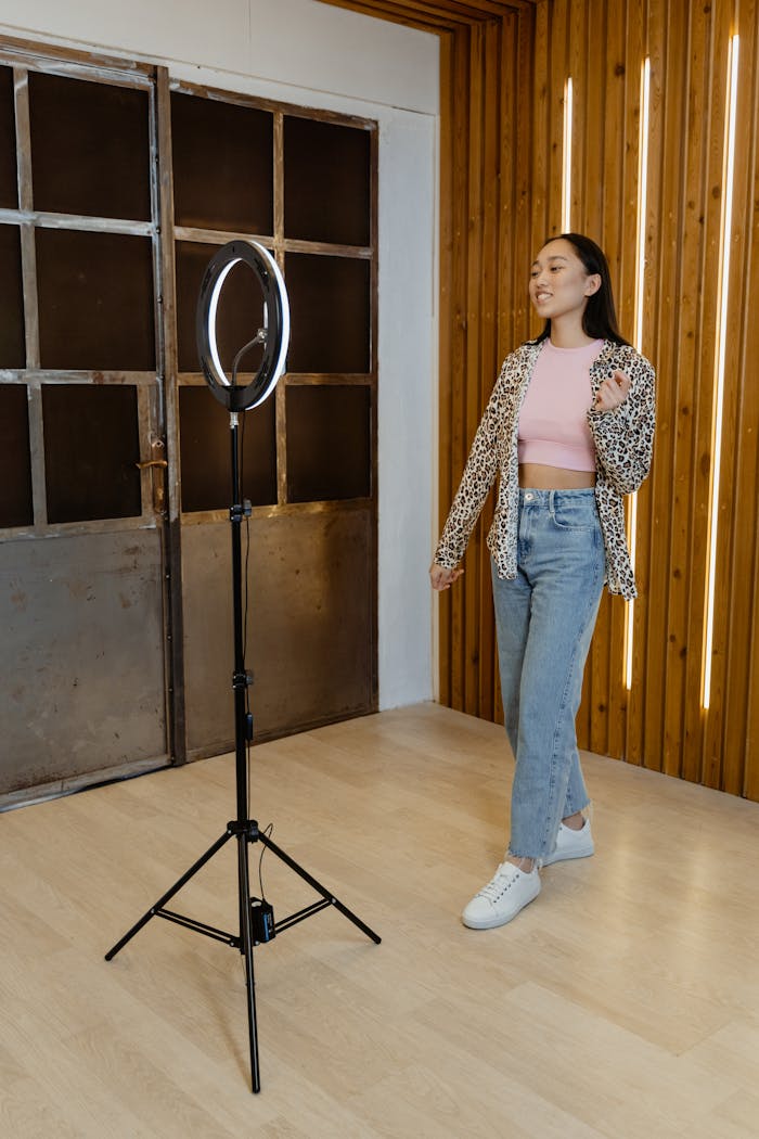 Services A young woman in casual attire dances joyfully in a modern studio with a ring light.